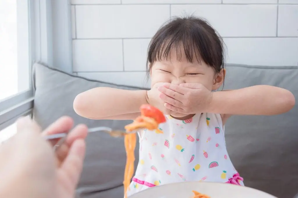 Child refusing to eat spaghetti offered by parent. This is an example of a skill targeted in the autism therapy in Toronto program at Side by Side Therapy. 