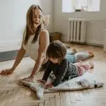 Parent or therapist doing a yoga routine with a child with autism.