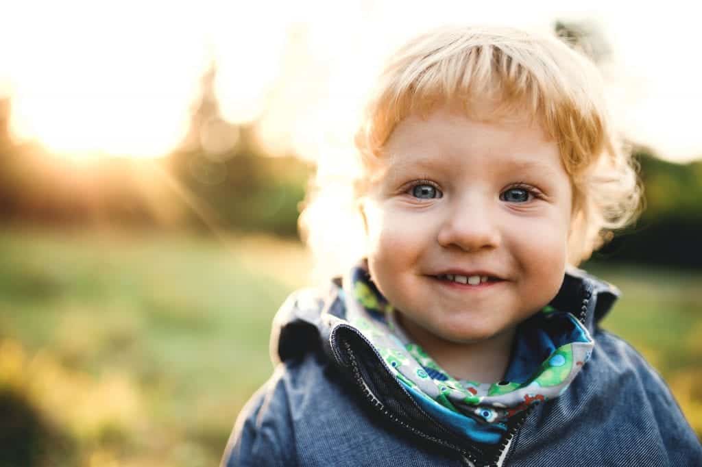 Toddler with autism smiling looking directly at the camera. 