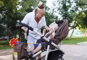 Woman walking with a baby in a stroller at the park during a respite services in Toronto session. 