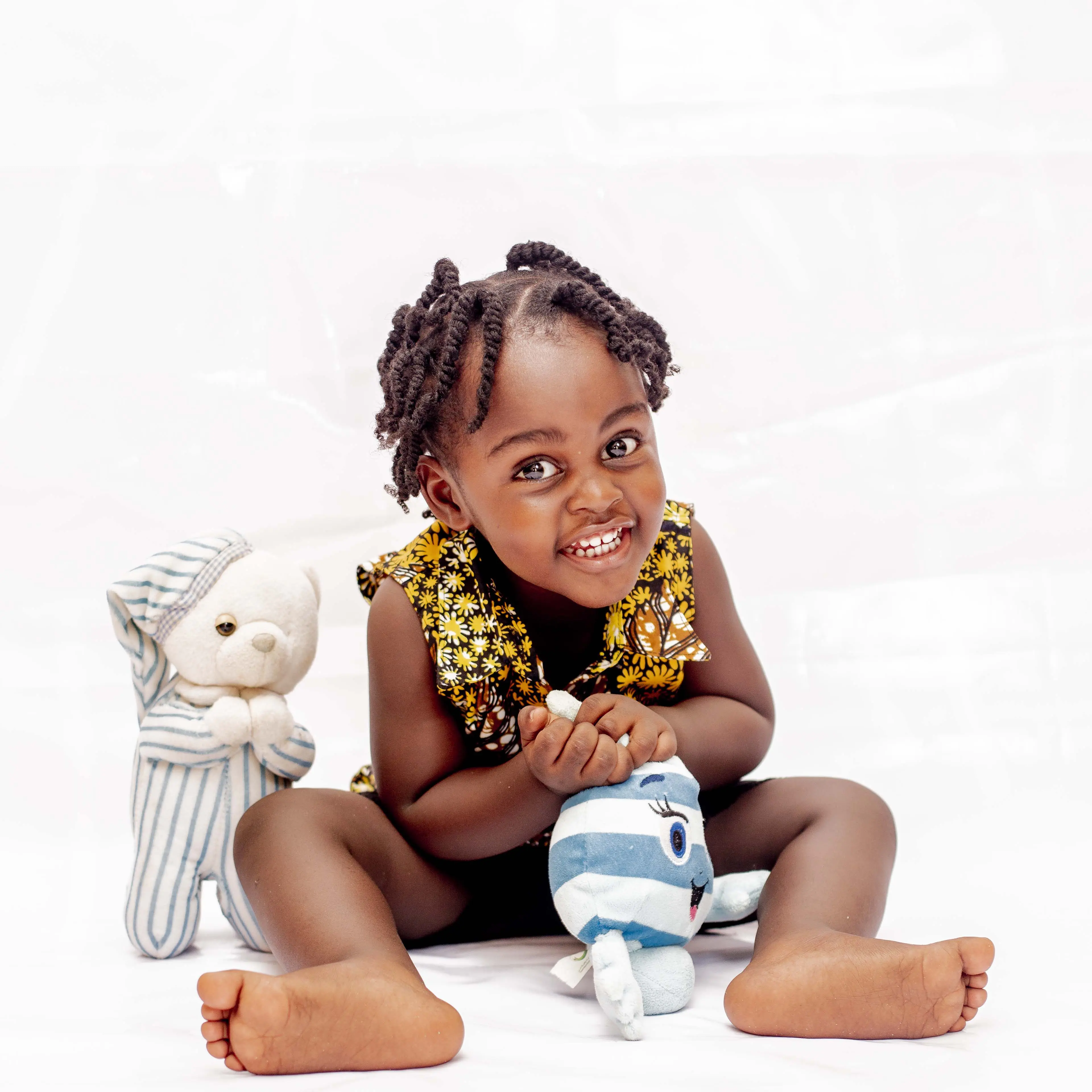 Black toddler smiling playing with toys in a white room during an early autism diagnosis. 