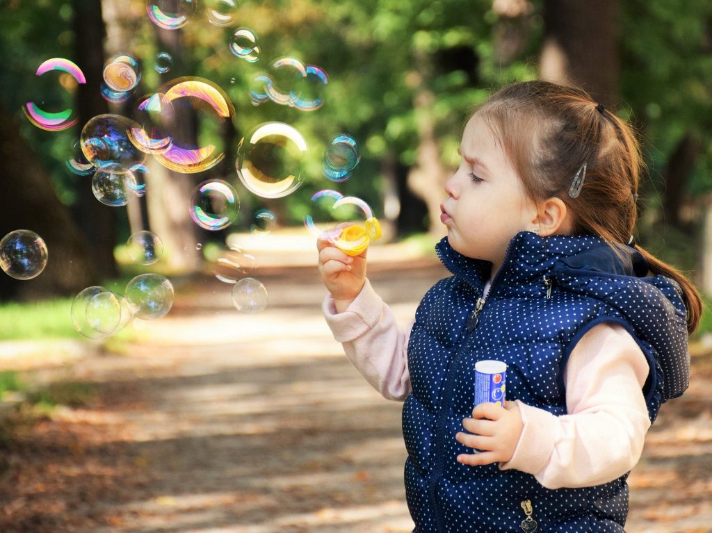 Toddler blowing bubbles. Should her parents try to cure her autism? 