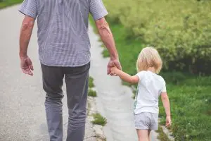 Father walking with daughter along the street. Autism severity levels aren't clear. 