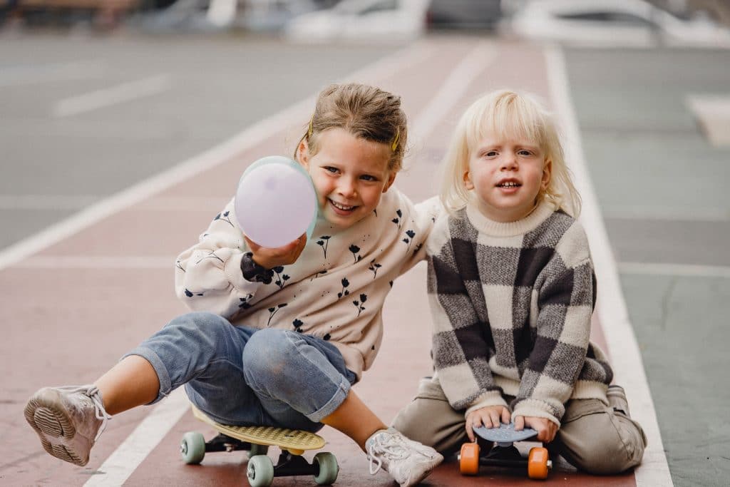 Kids during an OT session for autistic children, playing on skateboards. 